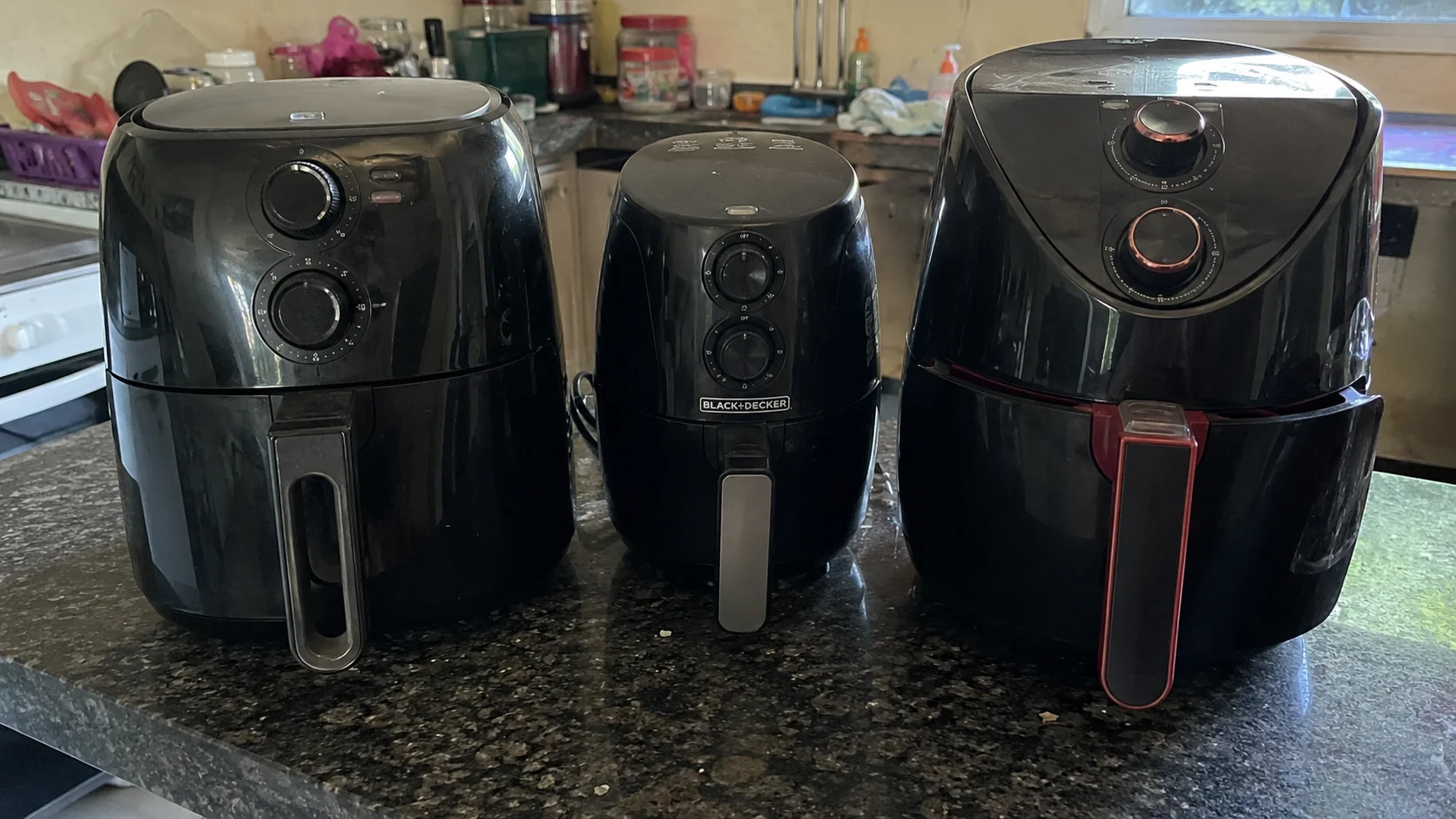 Comparativo real entre airfryers Elgin, Black+Decker e Philco sobre bancada de cozinha residencial durante teste de uso